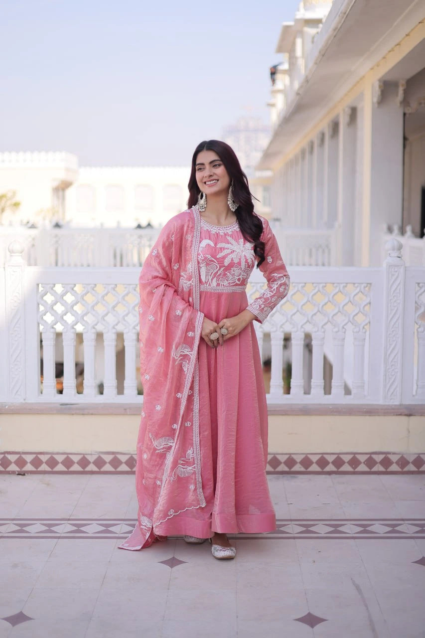 Woman in a pink traditional outfit standing on a balcony with a white building in the background